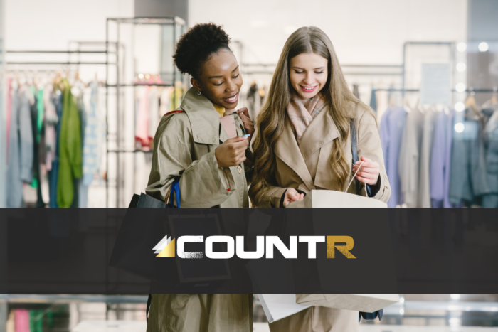 Two smiling women shopping in a fashion store, symbolizing improved customer engagement enabled by CountR footfall analytics