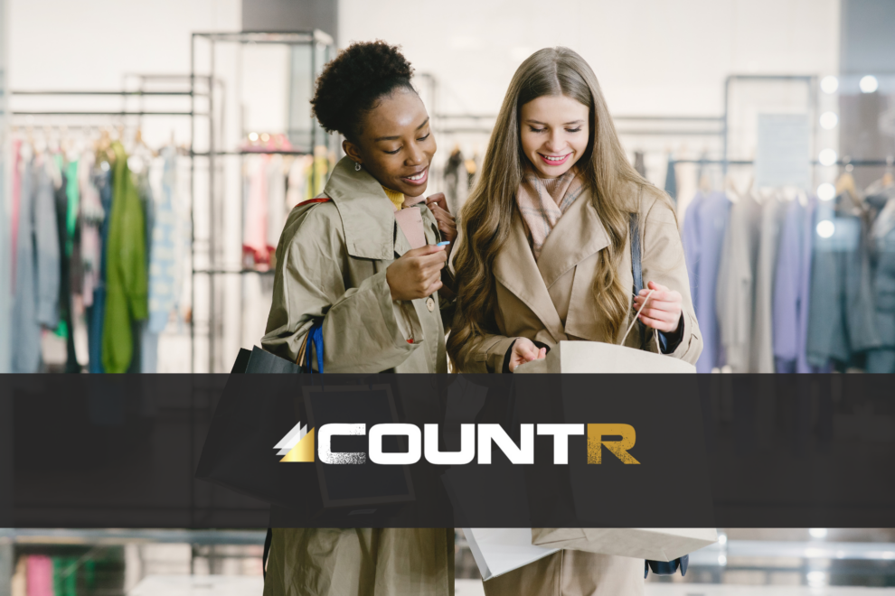 Two smiling women shopping in a fashion store, symbolizing improved customer engagement enabled by CountR footfall analytics