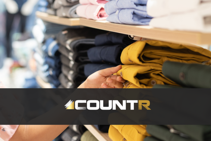 Customer hand selecting folded pants from a retail shelf in a clothing store