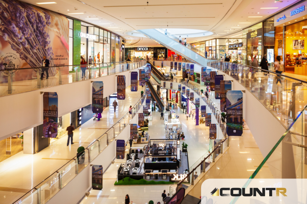 Interior view of a modern multi-level shopping mall with active shoppers and illuminated storefronts 