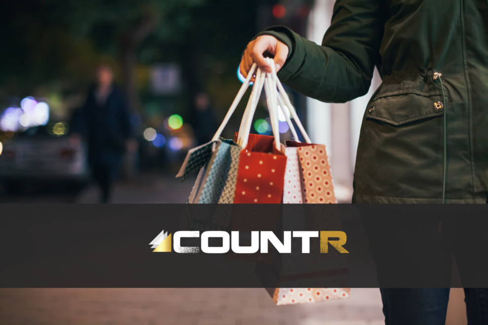 Person holding multiple shopping bags during the holiday season with CountR logo overlay