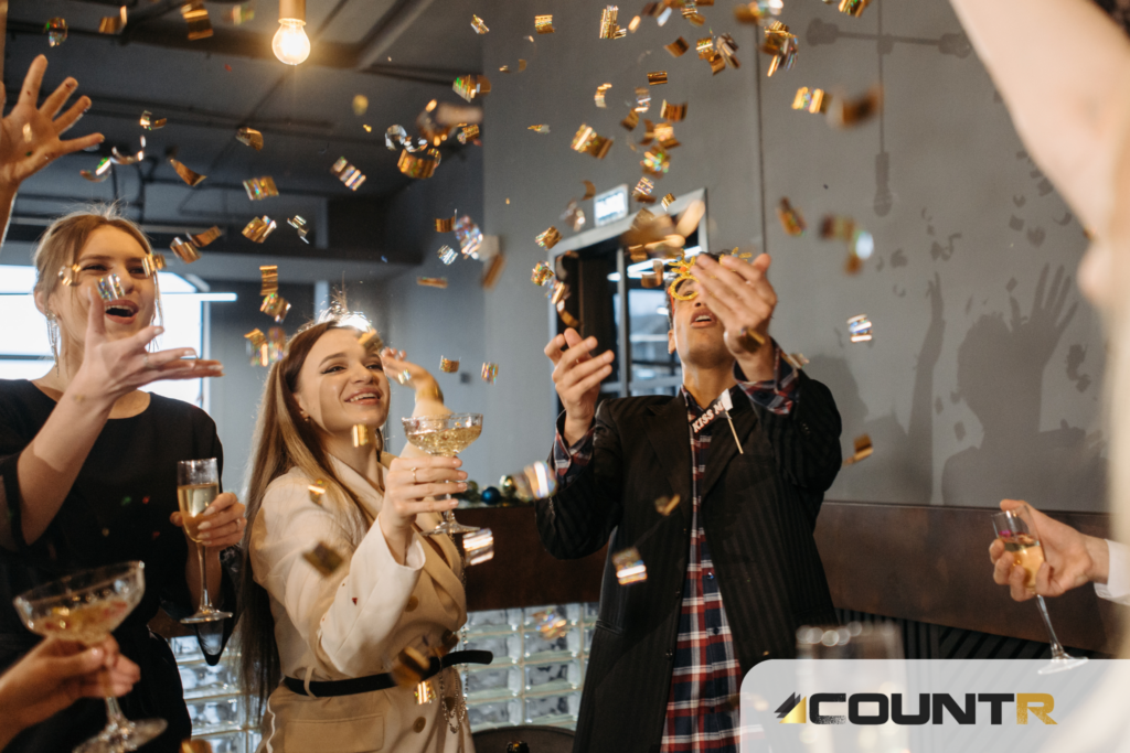 Group of people celebrating the holiday season with confetti and champagne, CountR logo in corner