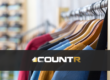 Clothing store rack with colorful shirts and the CountR logo representing reliable people counting systems.